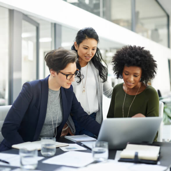 Three coworkers looking at a laptop.