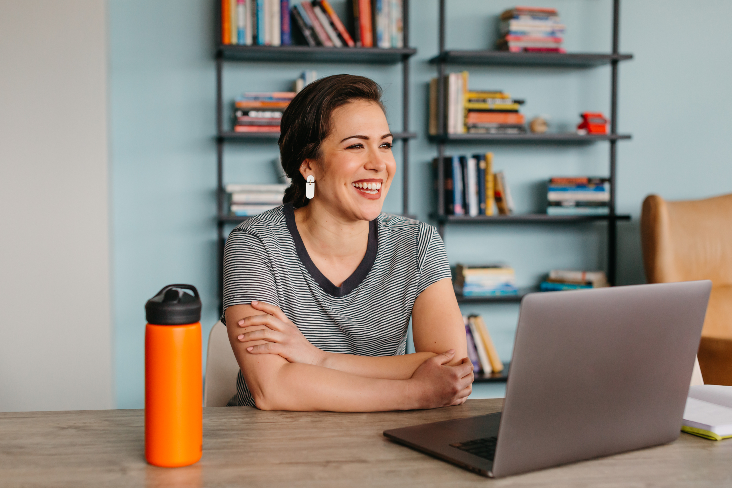 A woman in a home office seated in front of a laptop.