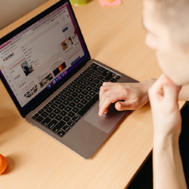 A man looking at computer and scrolling through a webpage.