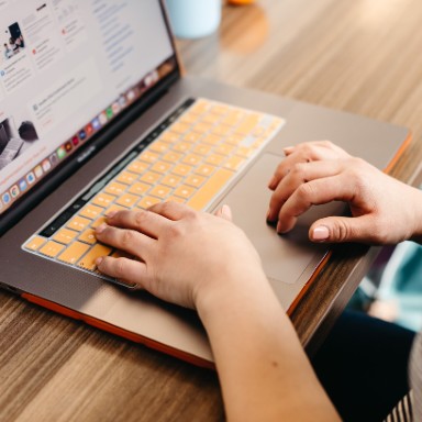 A pair of hands typing on a laptop keyboard.