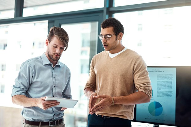 Two men look at a tablet screen