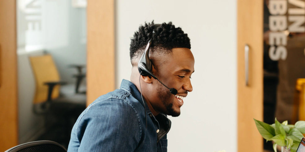 A smiling seated man with a headset on.