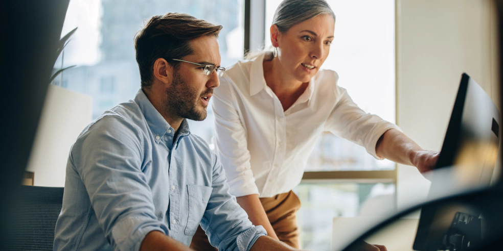 Two coworkers looking at a computer monitor.