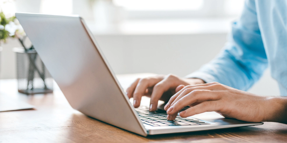 Close up of hands typing on laptop keyboard.