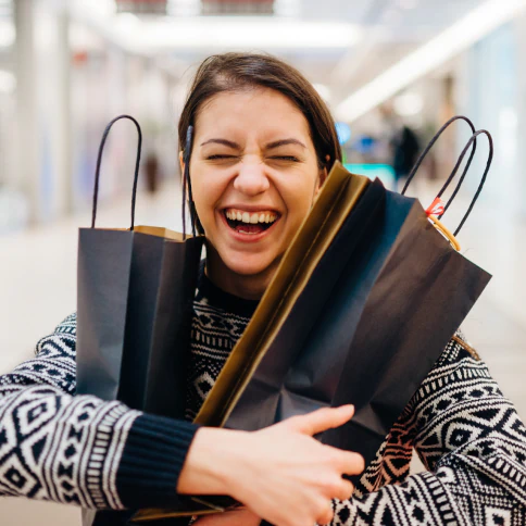 A very happy person holding shopping bags.