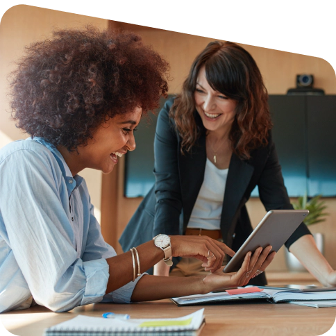 Two smiling women looking at a tablet.