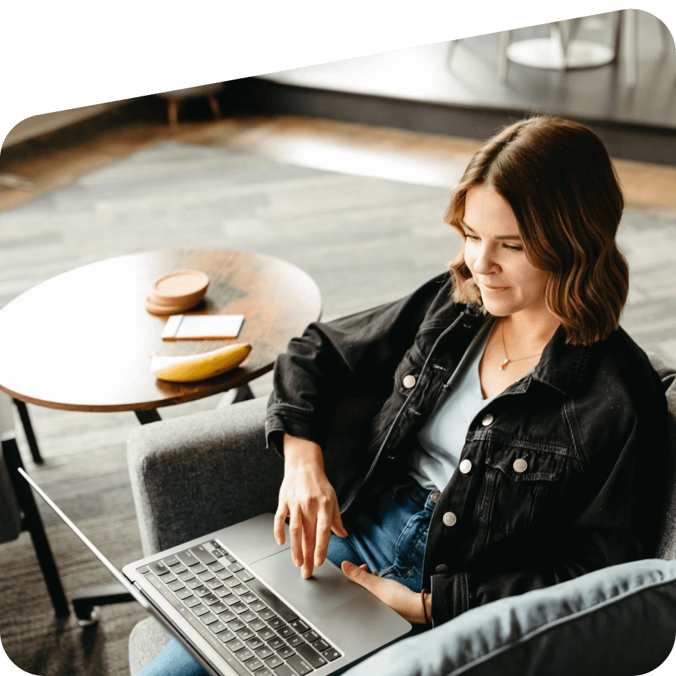 A seated woman browses on her laptop.