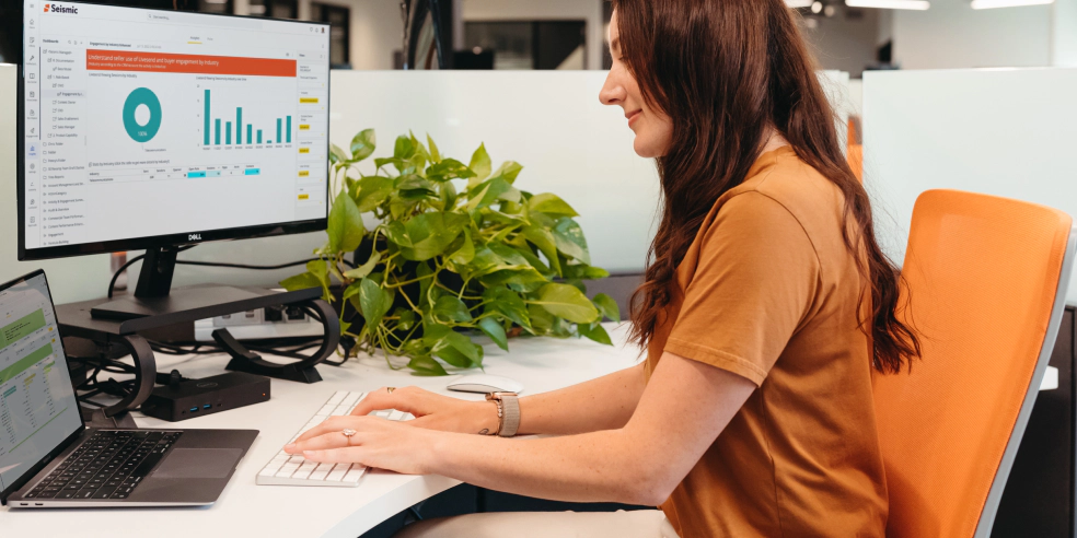 A woman sits at desk and types on a keyboard.